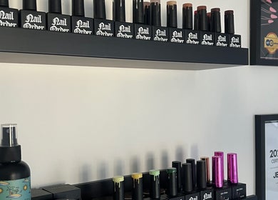 Nail polish collection on shelves at Nails By Jess, St Austell, England, GB. Certification awards displayed.
