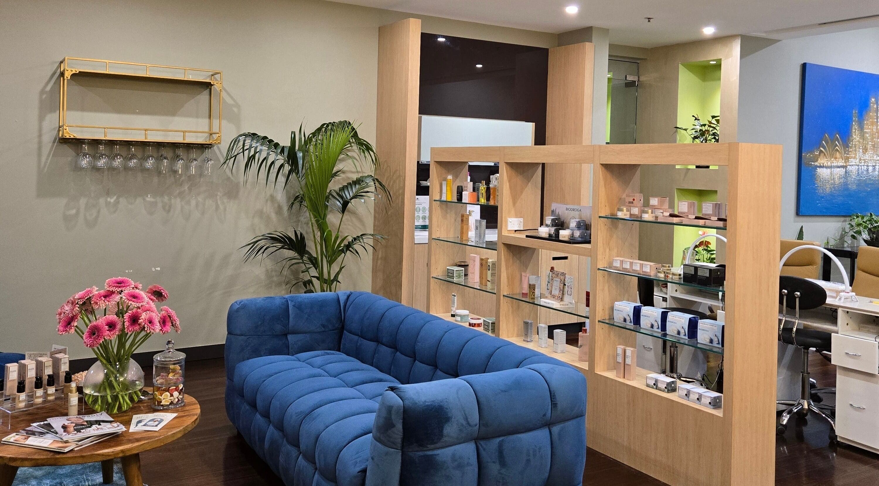 Stylish lounge at Glow District Beauty with blue sofa, floral decor, in Sydney, New South Wales, AU.