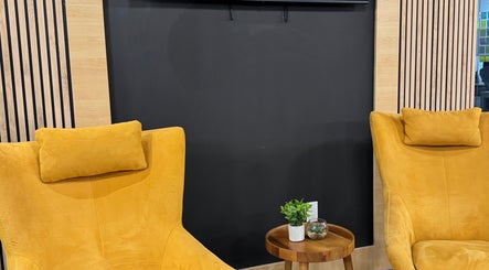 Bright yellow chairs with a wooden table at LV Aestheticca in Toronto, Ontario, CA, creating a cozy nook.