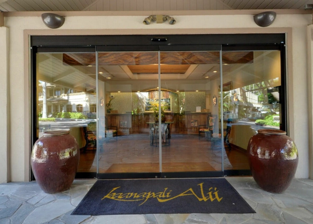 Glass entrance of Kaanapali Alii Wellness in Lahaina, Hawaii, US, with large decorative pots on each side.
