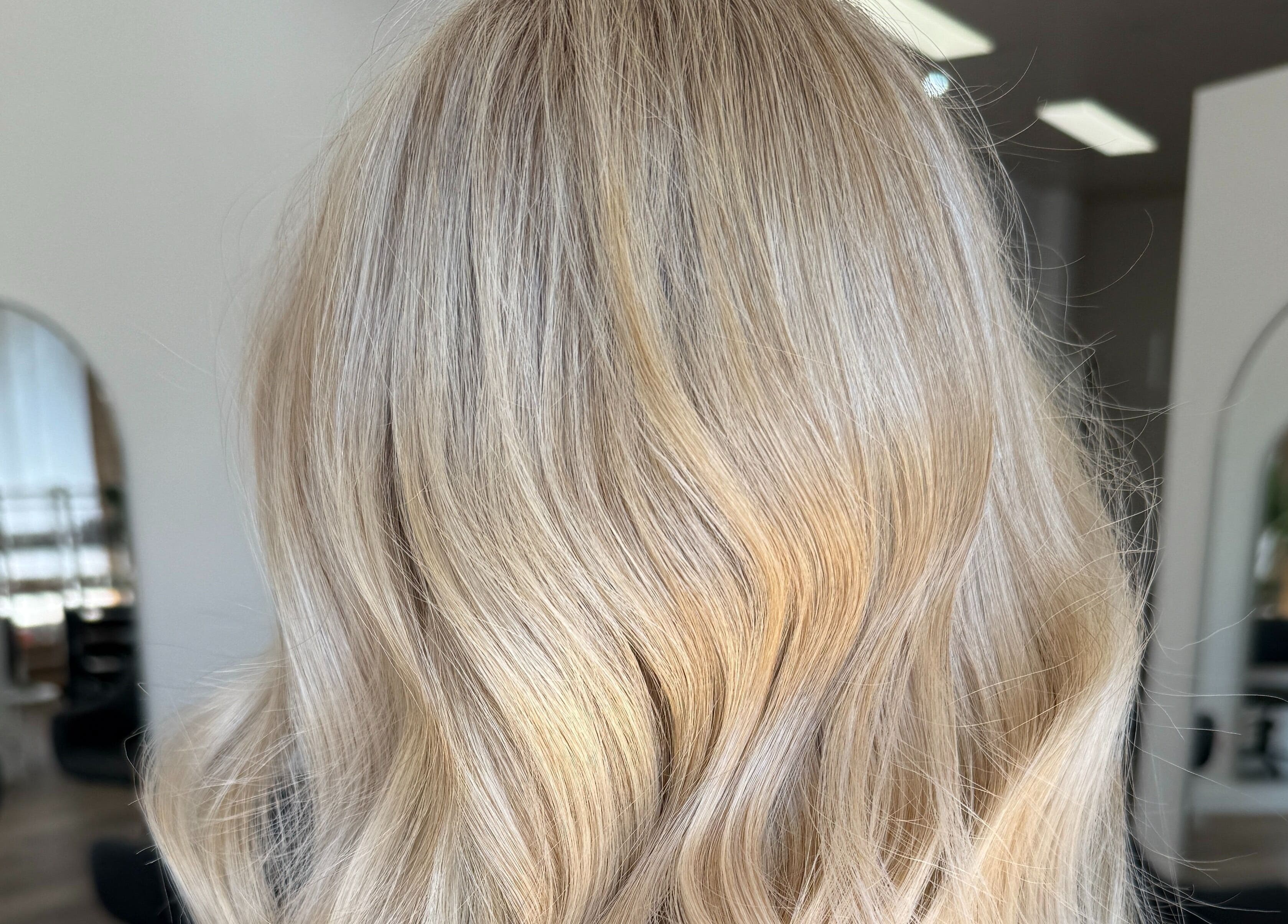 Blonde wavy hairstyle at Hair By Jenna Lutgens, Melbourne, Victoria, AU, showcasing elegant salon ambiance.