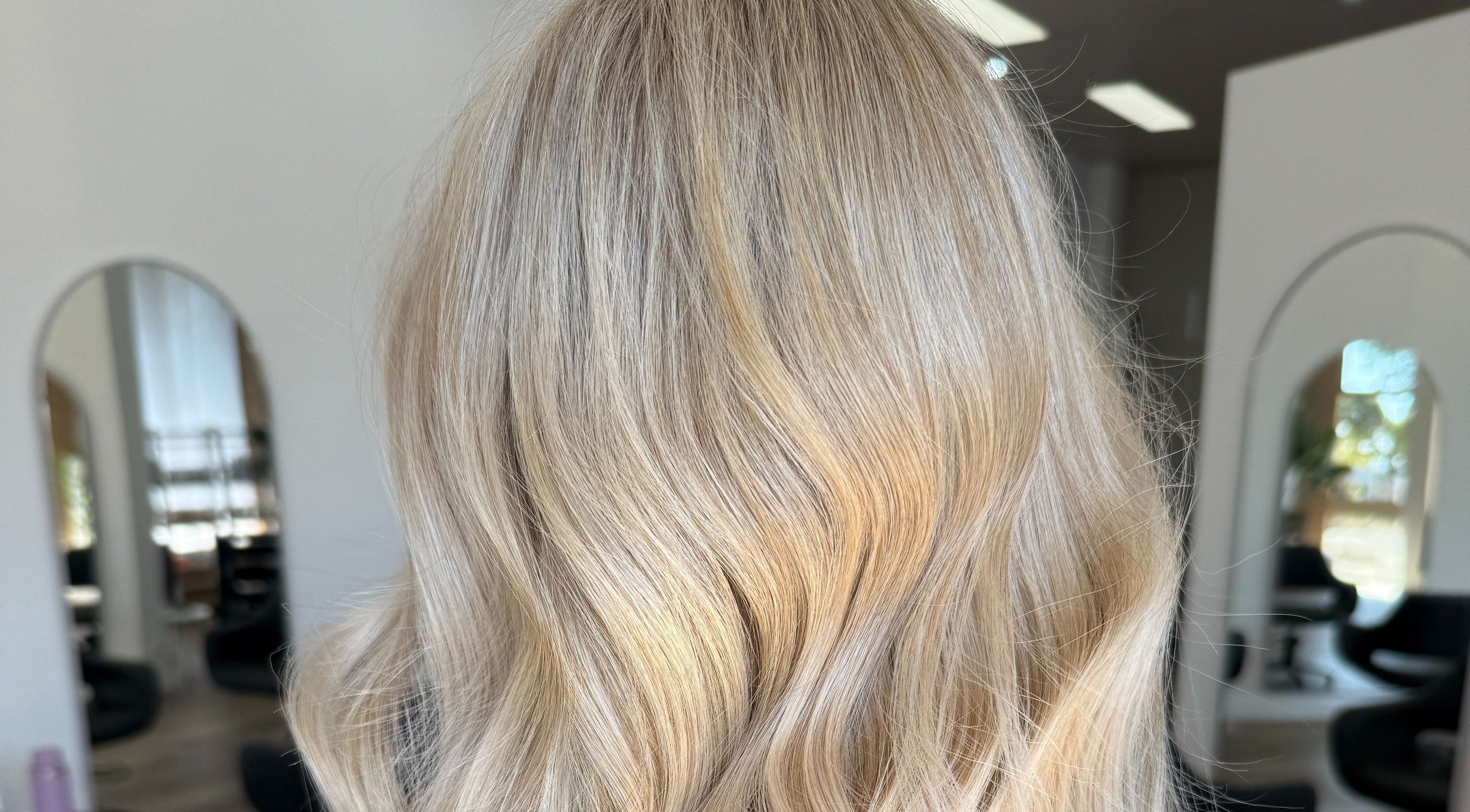 Blonde wavy hairstyle at Hair By Jenna Lutgens, Melbourne, Victoria, AU, showcasing elegant salon ambiance.