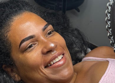 Happy client with perfect brows at XBrows, Orlando, Florida, US, admiring results in ornate mirror.