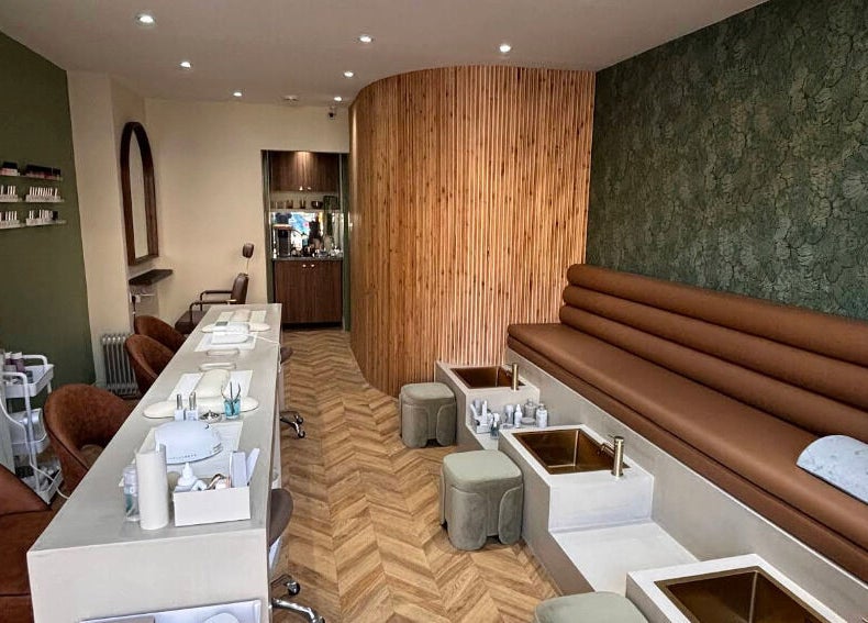 Interior of SOAK in London, England, GB, showcasing chic nail stations and plush seating under soft lighting.