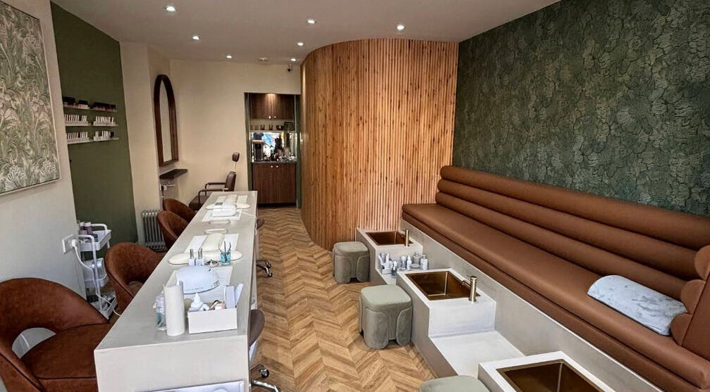 Interior of SOAK in London, England, GB, showcasing chic nail stations and plush seating under soft lighting.
