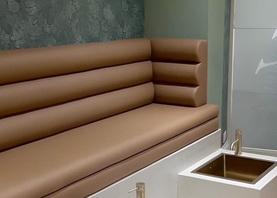 Luxurious seating area at SOAK, London, England, GB featuring plush brown cushions and a modern sink.