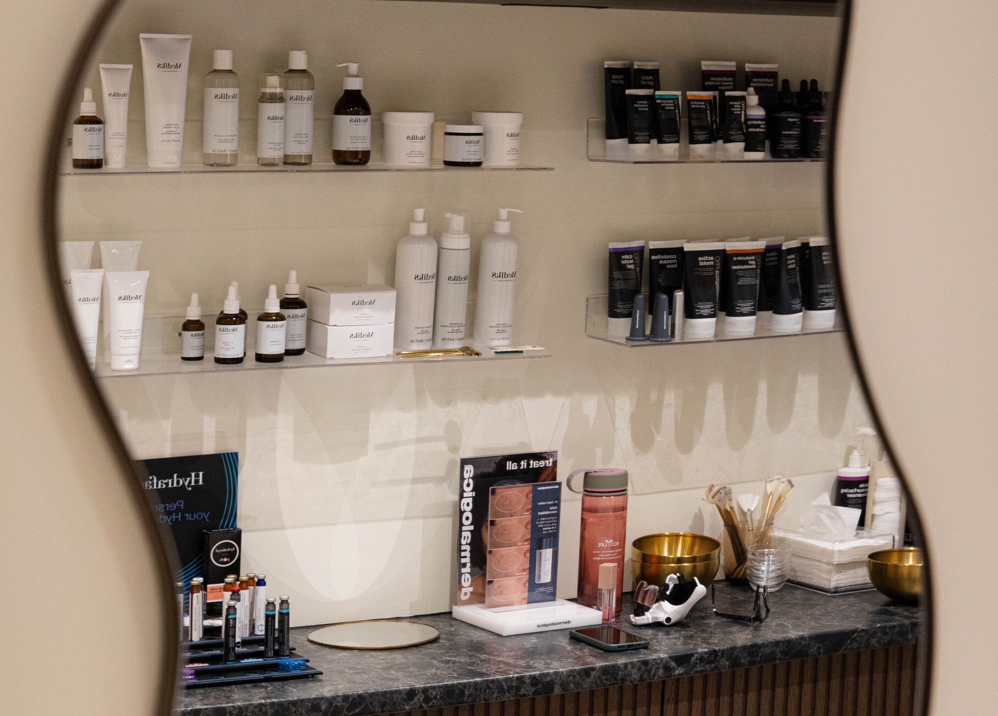 Beauty products elegantly displayed at SOAK, London, England, GB, seen through a curved mirror reflection.