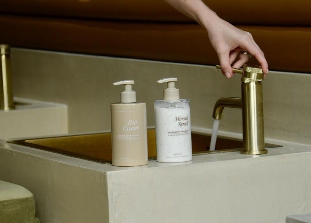 Luxurious handwash area in SOAK, London, England, GB, with gold faucet and skincare products.