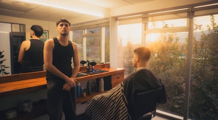 Interior de Cráneo Barbershop en Las Condes, Región Metropolitana, CL con barbero y cliente al atardecer.