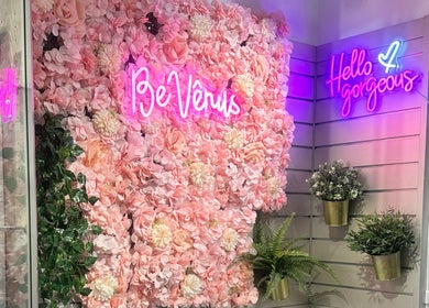 Rosa Blumenwand mit leuchtendem Logo von BE Vênus - Esthetic Salon KLG, Thun, Bern, CH.