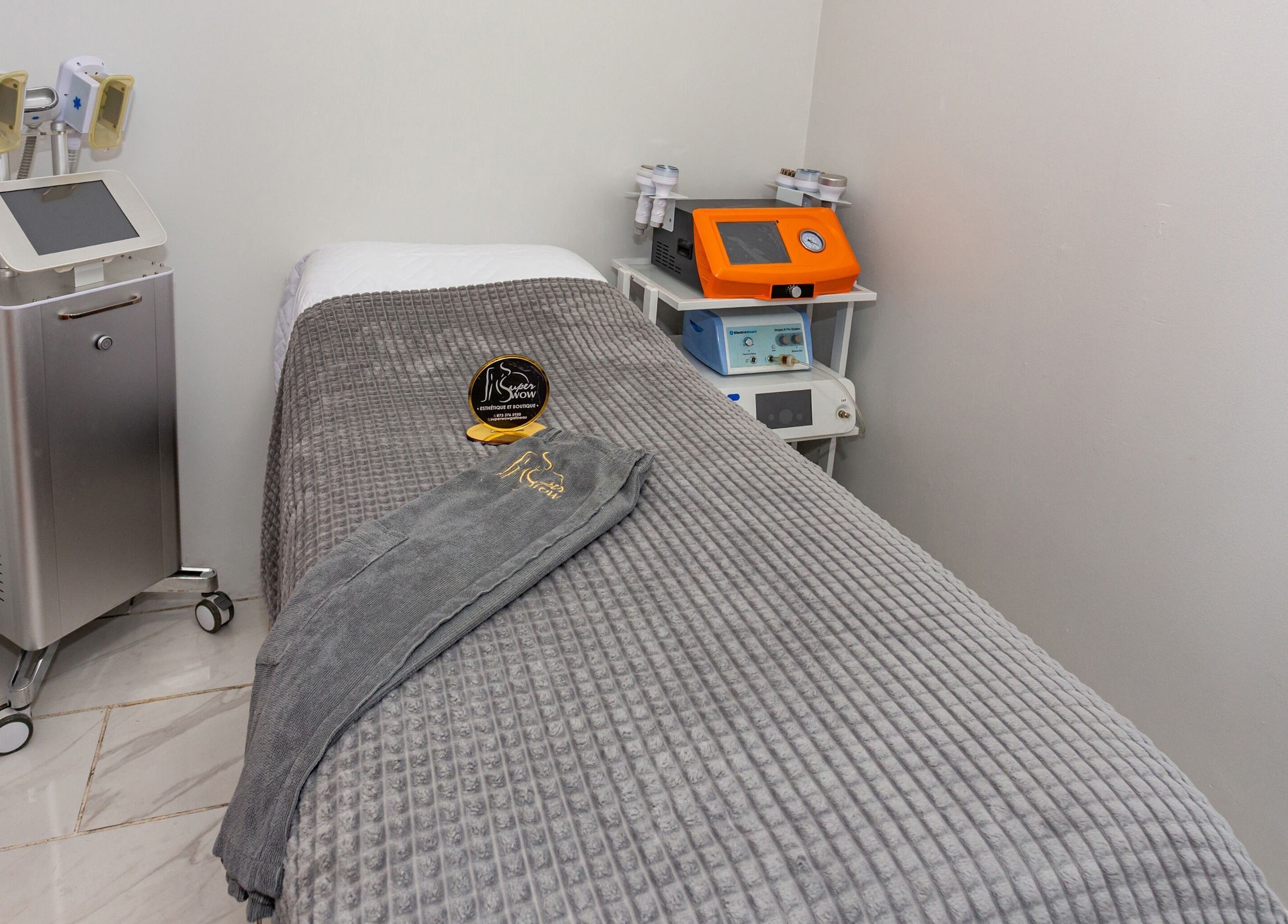 Salle de soins moderne au Super Wow Studio à Gatineau, Québec, CA, avec table de massage et équipements spécialisés.