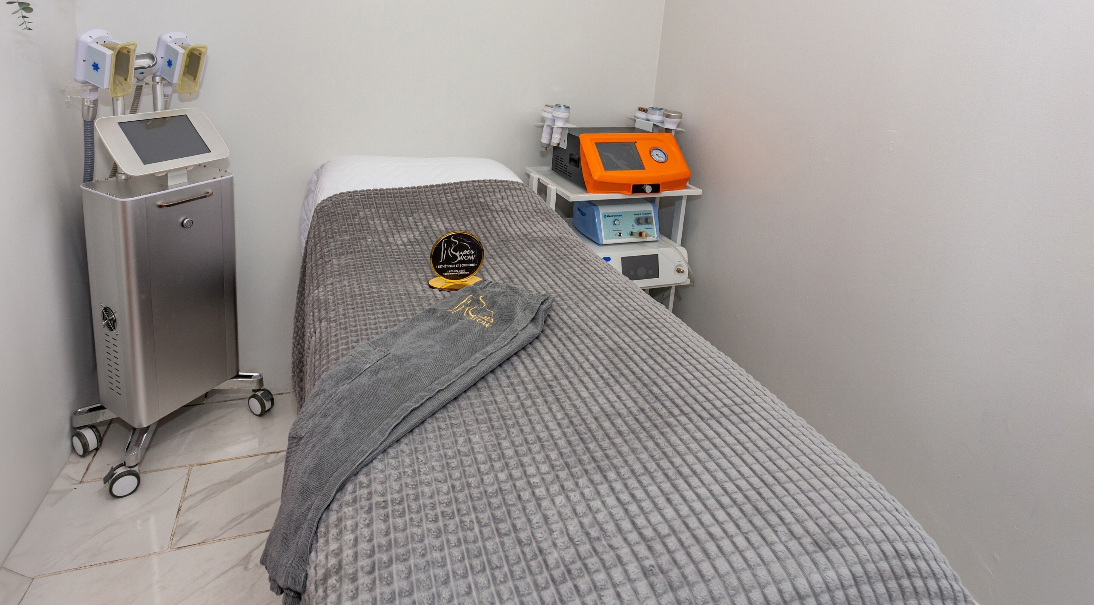 Salle de soins moderne au Super Wow Studio à Gatineau, Québec, CA, avec table de massage et équipements spécialisés.