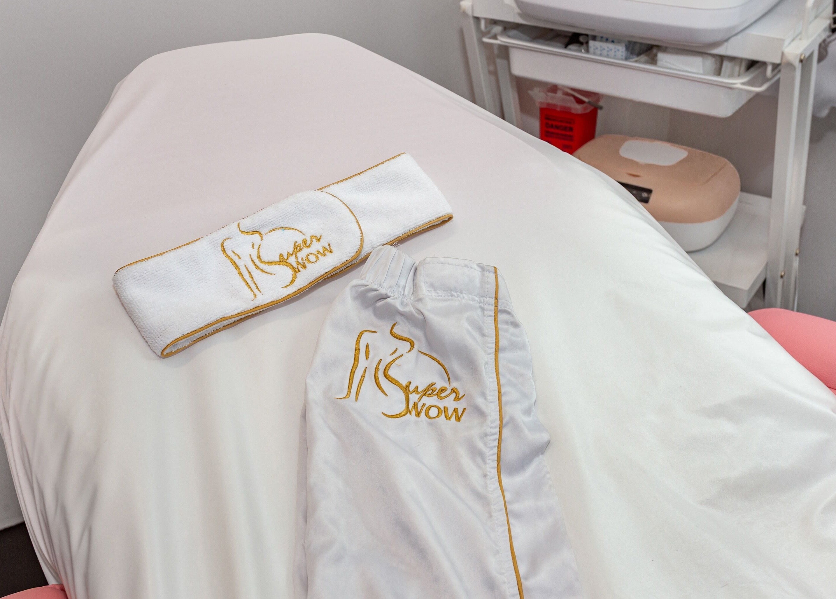 Serviette et pantalon de spa brodés 'Super Wow (Longueuil)' sur un lit de traitement à Longueuil, Québec, CA.
