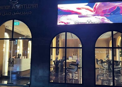 Night view of Generation Gentleman Barbershop in دبي, دبي, AE with stylish interior through arched windows.