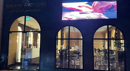 Night view of Generation Gentleman Barbershop in دبي, دبي, AE with stylish interior through arched windows.