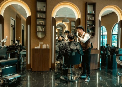Stylist at Generation Gentleman Barbershop in دبي, دبي, AE, crafting a modern hairstyle with precision.