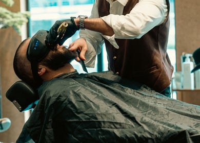 Expert barber at Generation Gentleman Barbershop, دبي, دبي, AE, precisely trimming a client's beard.