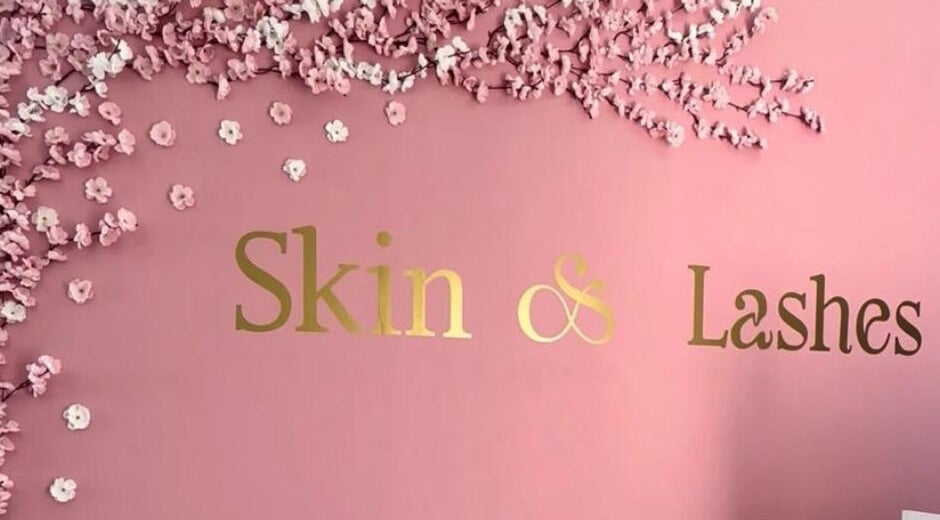 Logotipo dorado de Skin & Lashes en una pared rosa floral en Santiago De Querétaro, Querétaro, MX.