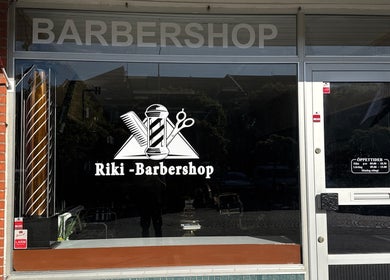 Barbershop fasad i Ängelholm, Skåne Län, SE. Stor logotyp och öppettider på skyltfönstret.