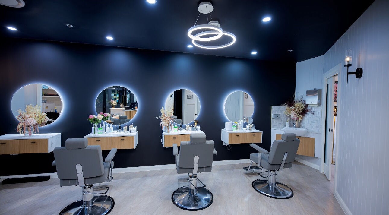 Elegant beauty salon interior at San's Threadz & Beauty, Jesmond, New South Wales, AU with stylish chairs and lit mirrors.