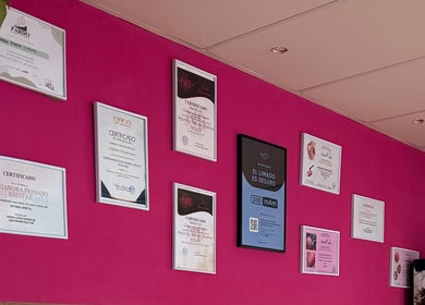 Certificados en una pared rosa del Alejandra Peinado Centro Estético en Pinos Puente, Andalucía, ES.