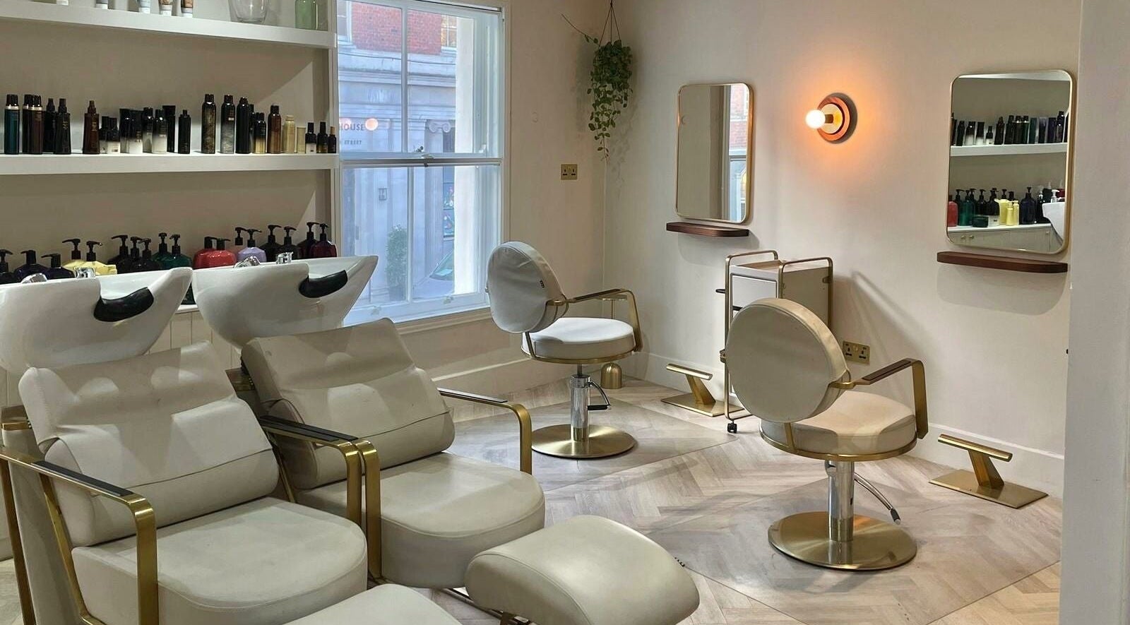 Bright interior of Luna & Wilde Belgravia, a stylish salon in London, England with modern chairs and products.