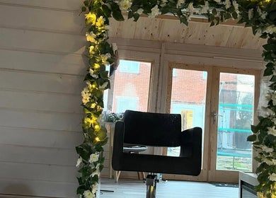Elegant salon chair and flower-adorned mirror at Mrs Mabbley Hair Studios, Aldershot, England, GB.