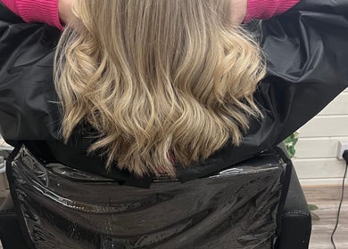Blonde wavy hairstyle at Mrs Mabbley Hair Studios, Aldershot, England, GB. A view from behind on salon chair.