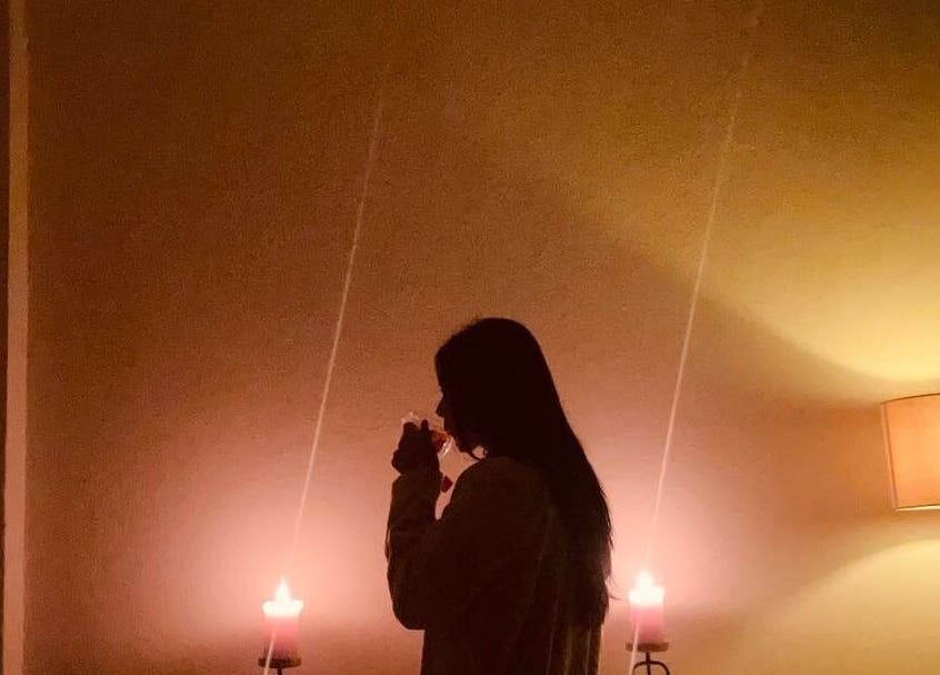 Mujer disfrutando de una bebida caliente a la luz de velas en Serenity Spa, Loreto, Baja California Sur, MX.