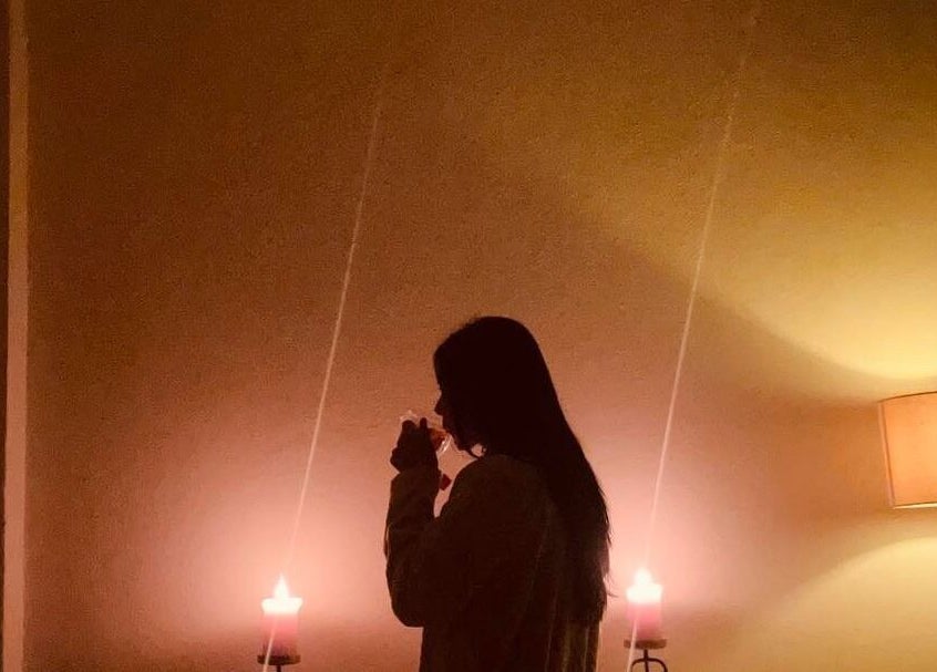 Mujer disfrutando de una bebida caliente a la luz de velas en Serenity Spa, Loreto, Baja California Sur, MX.