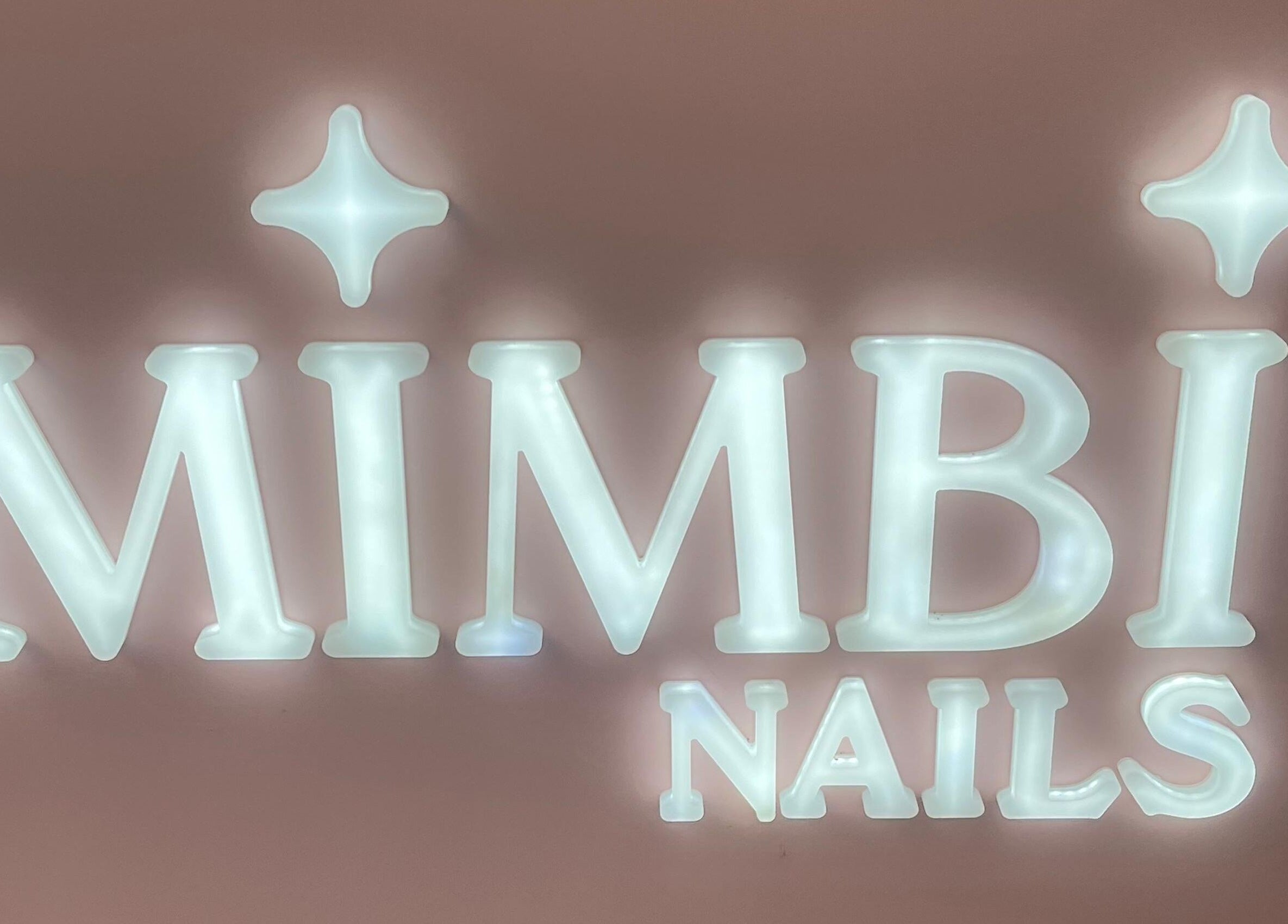Cartel iluminado de Mimbi Nails en Lleida, Catalunya, ES, destacándose sobre un fondo rosado.