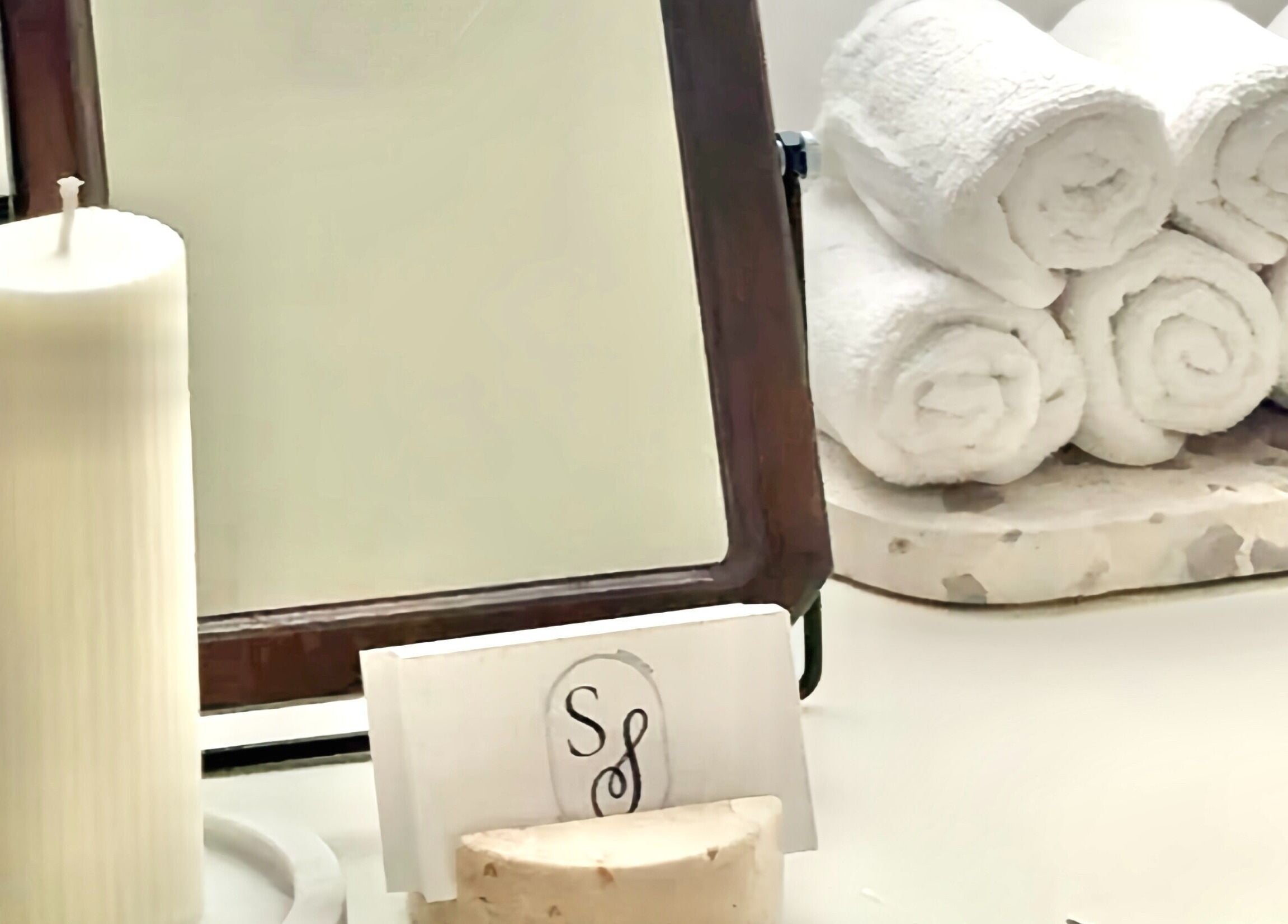 Elegant spa setup at Studio Silk, Melbourne Victoria AU with candle, mirror, and rolled towels.