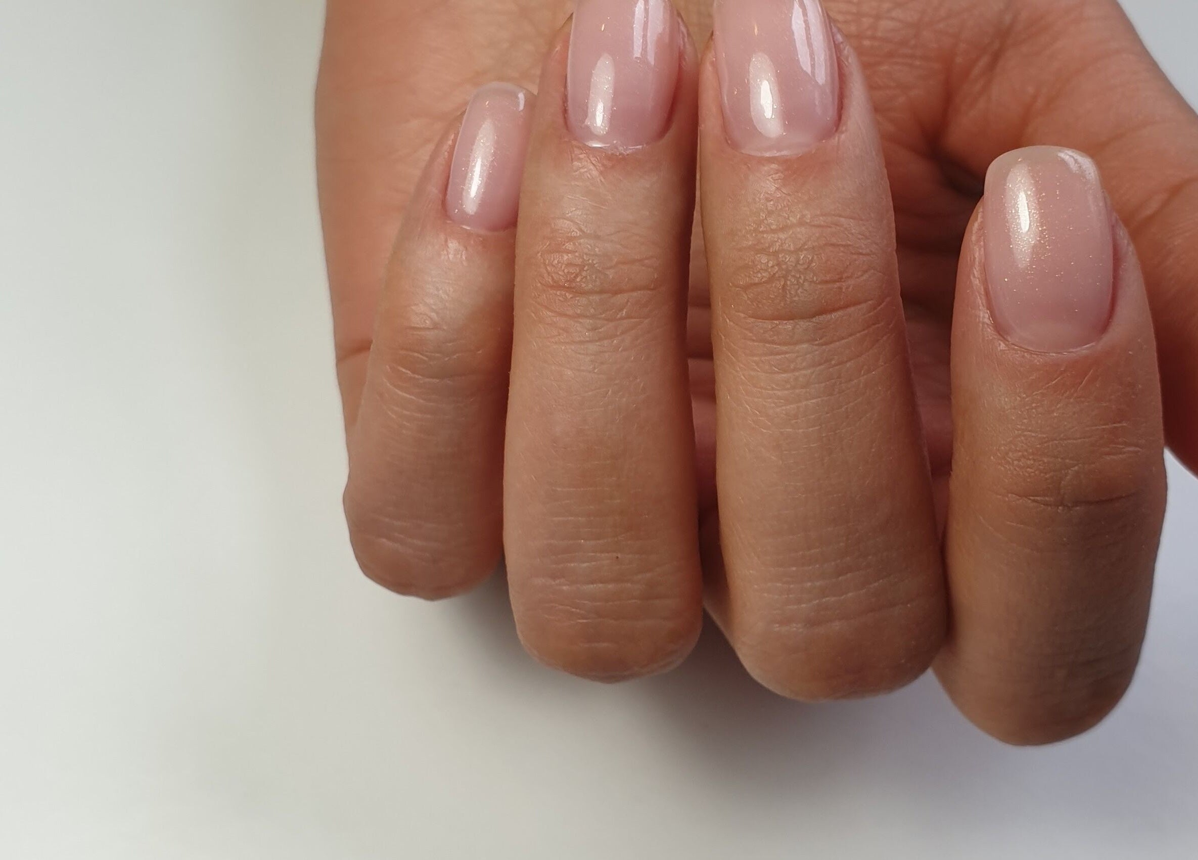Manicured hand with soft pink polish at Chique Nail Studio, London, England, GB.