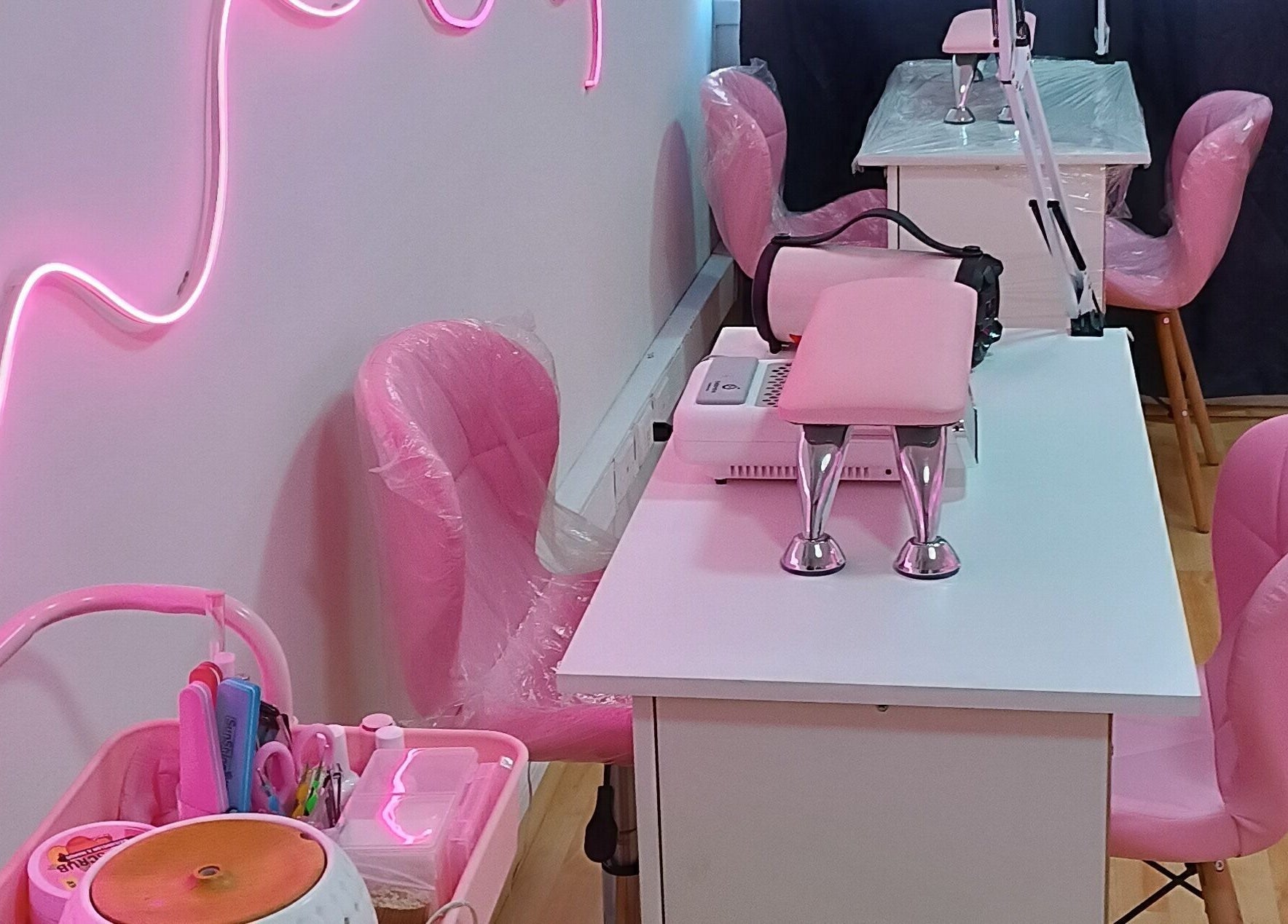 Interior de YM NAILS STUDIO en Santiago, Región Metropolitana, CL, con sillas y luces rosas vibrantes.