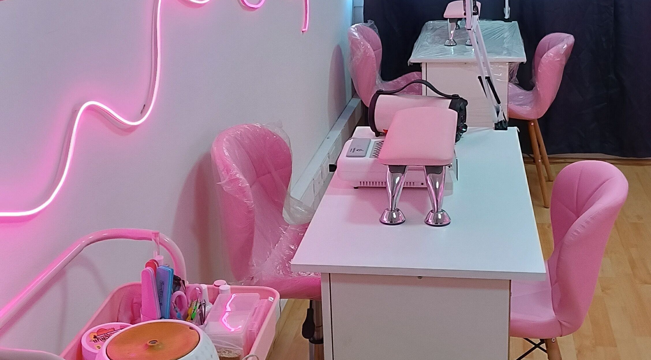 Interior de YM NAILS STUDIO en Santiago, Región Metropolitana, CL, con sillas y luces rosas vibrantes.