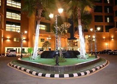Night view of Ezees Beauty & Spa courtyard, Al Khobar, Eastern Province, SA with illuminated palm trees.