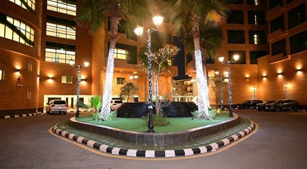 Night view of Ezees Beauty & Spa courtyard, Al Khobar, Eastern Province, SA with illuminated palm trees.