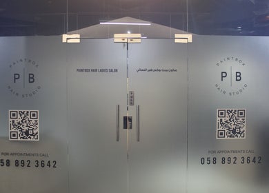 Elegant glass doors at Paintbox Hair Studio in Dubai, Dubai, AE with studio logo and contact details.