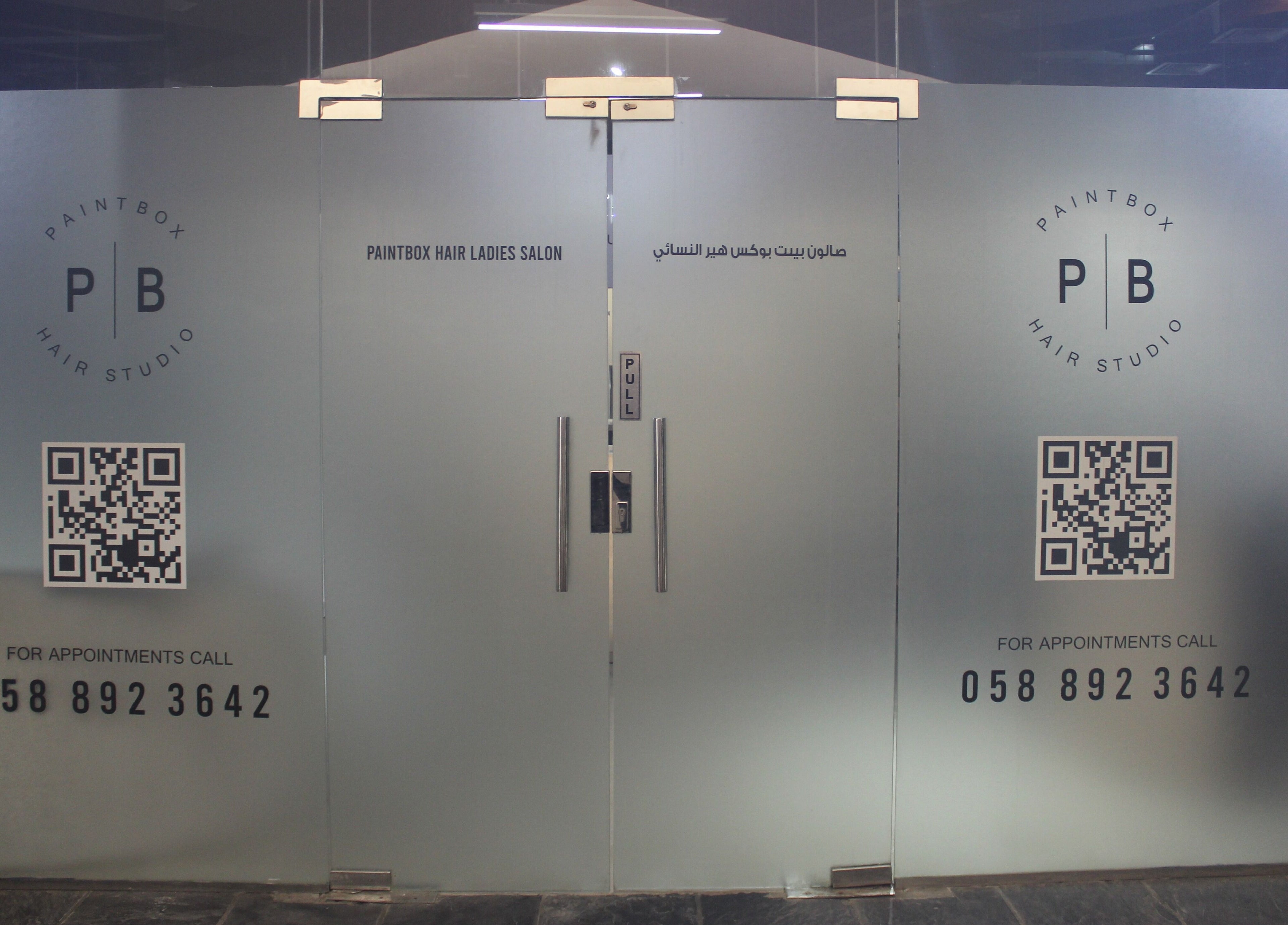 Elegant glass door entrance of Paintbox Hair Studio in Dubai, Dubai, AE, displaying studio logo and contact info.