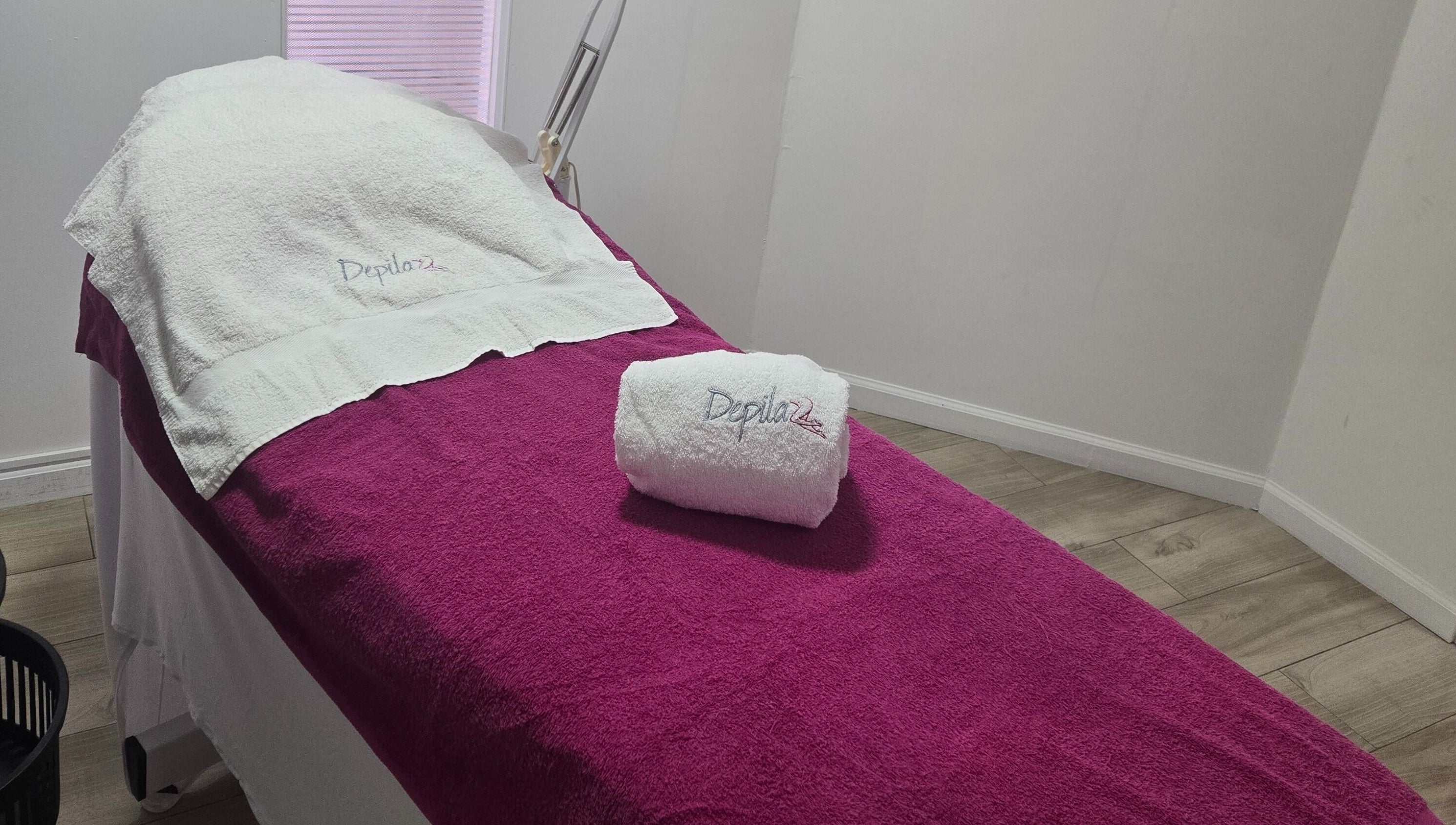 Camilla de tratamiento en Depila2, en Willemstad, CW, con toalla blanca y manto púrpura.