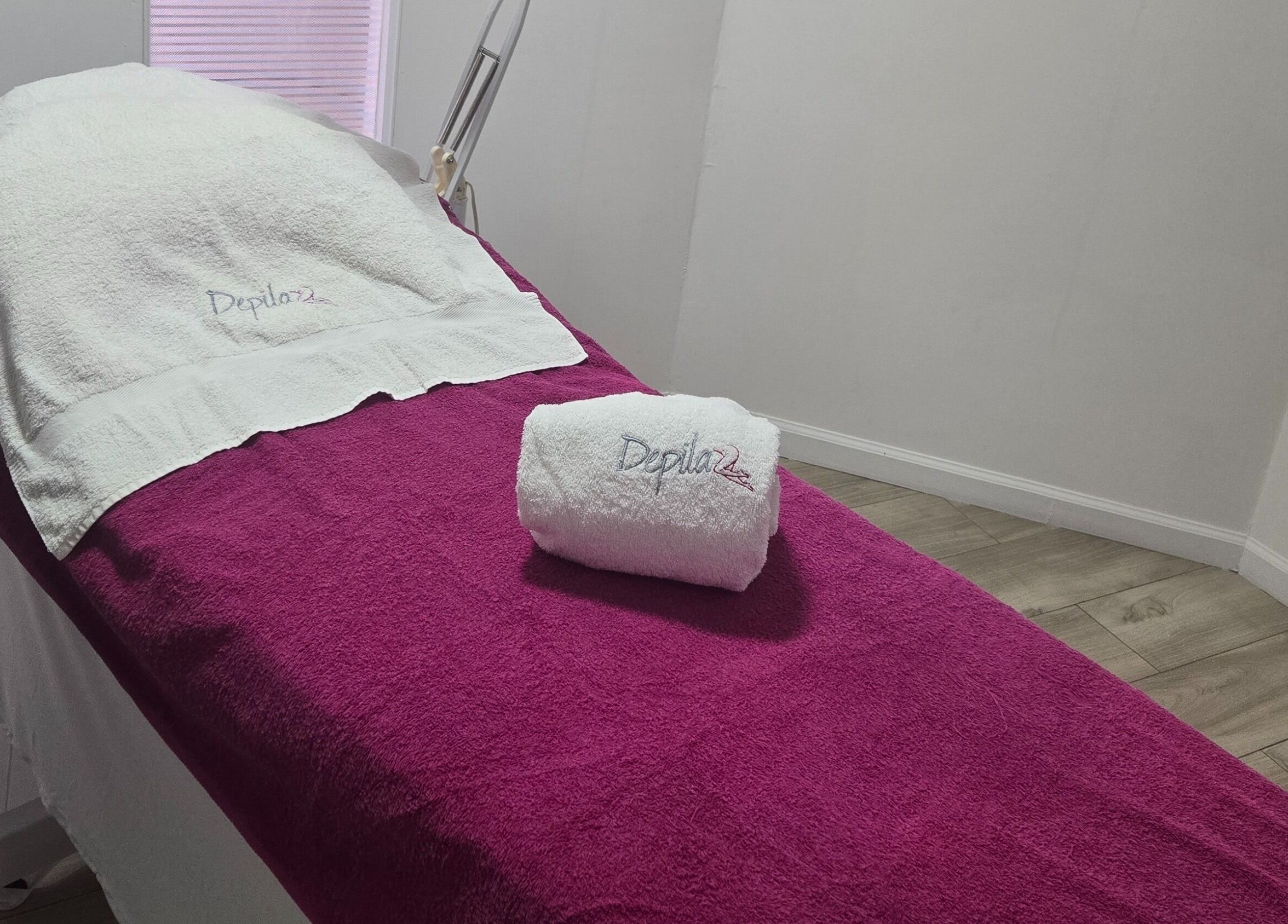 Camilla de tratamiento en Depila2, en Willemstad, CW, con toalla blanca y manto púrpura.