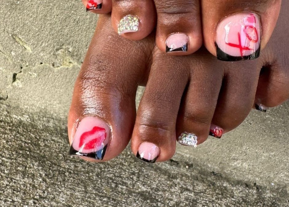 Stylish toenail art at Nail Therapy, Laborie, Laborie, LC, featuring red and black designs with glitter.