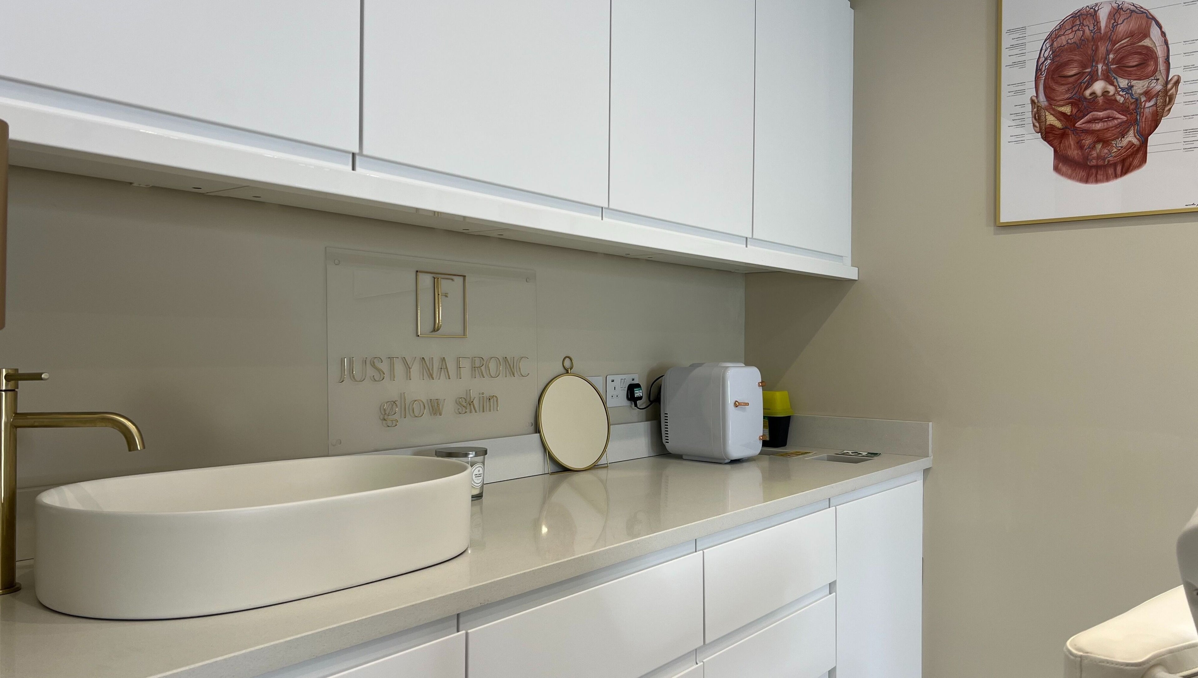 Modern counter at Glow Skin Justyna Fronc, London, England, GB, featuring a sleek white sink and gold faucet.