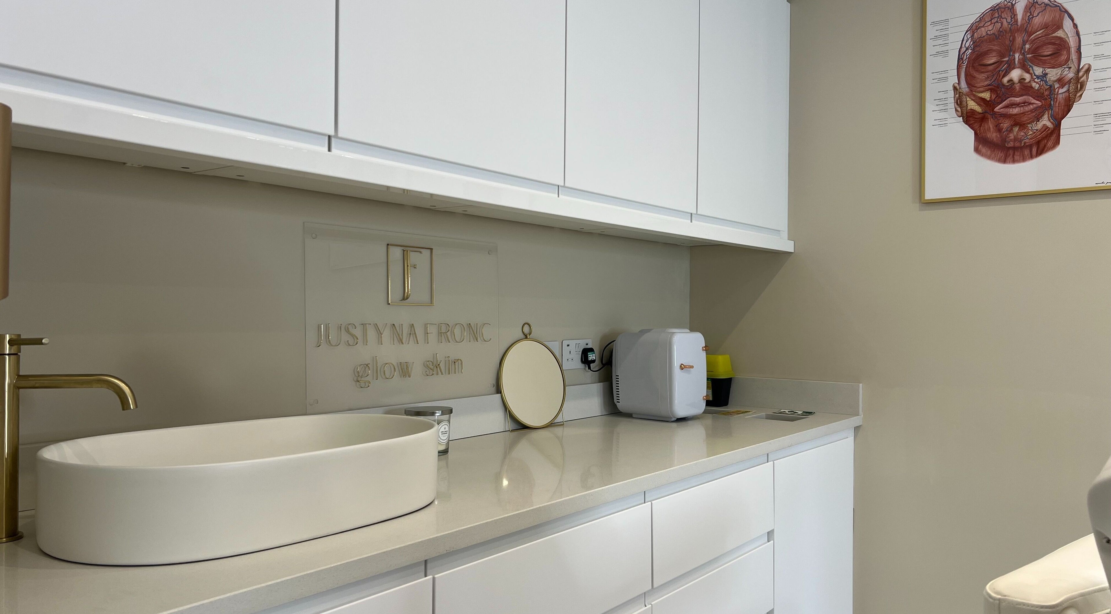 Modern counter at Glow Skin Justyna Fronc, London, England, GB, featuring a sleek white sink and gold faucet.