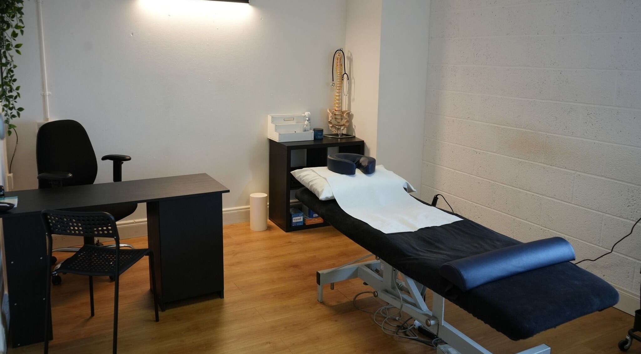 Treatment room at Optimal Health Injury Clinic, Claremorris, County Mayo, IE, featuring a massage table and desk.