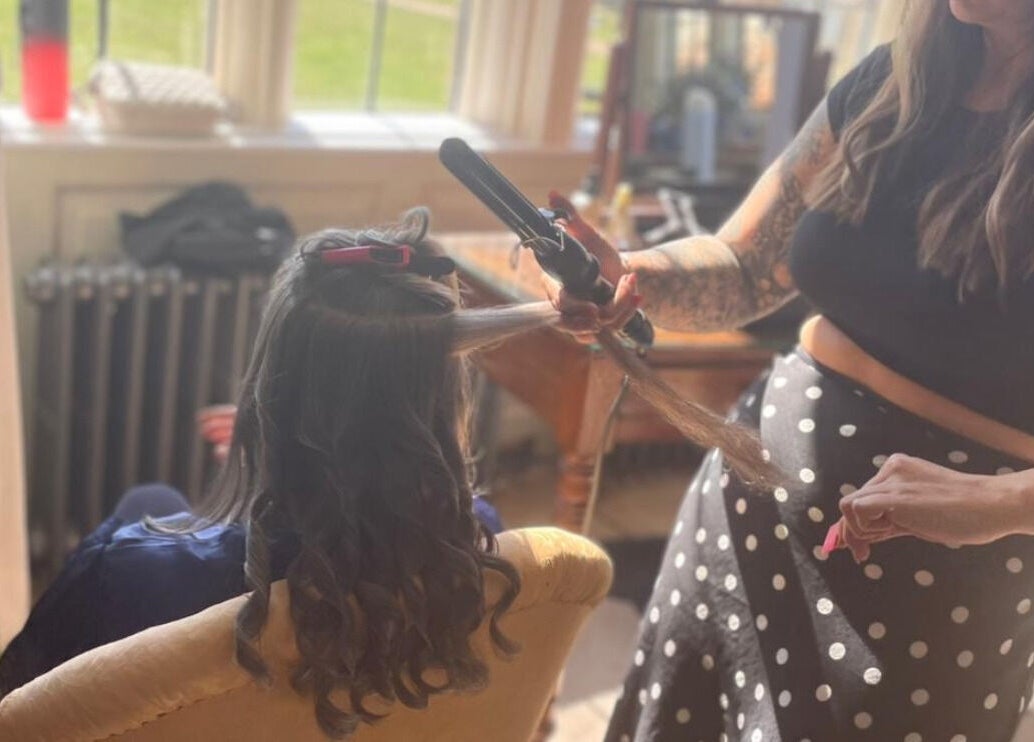 Hair stylist at HairbyAmiEileen in Basingstoke, England, curling a client's hair with precision.