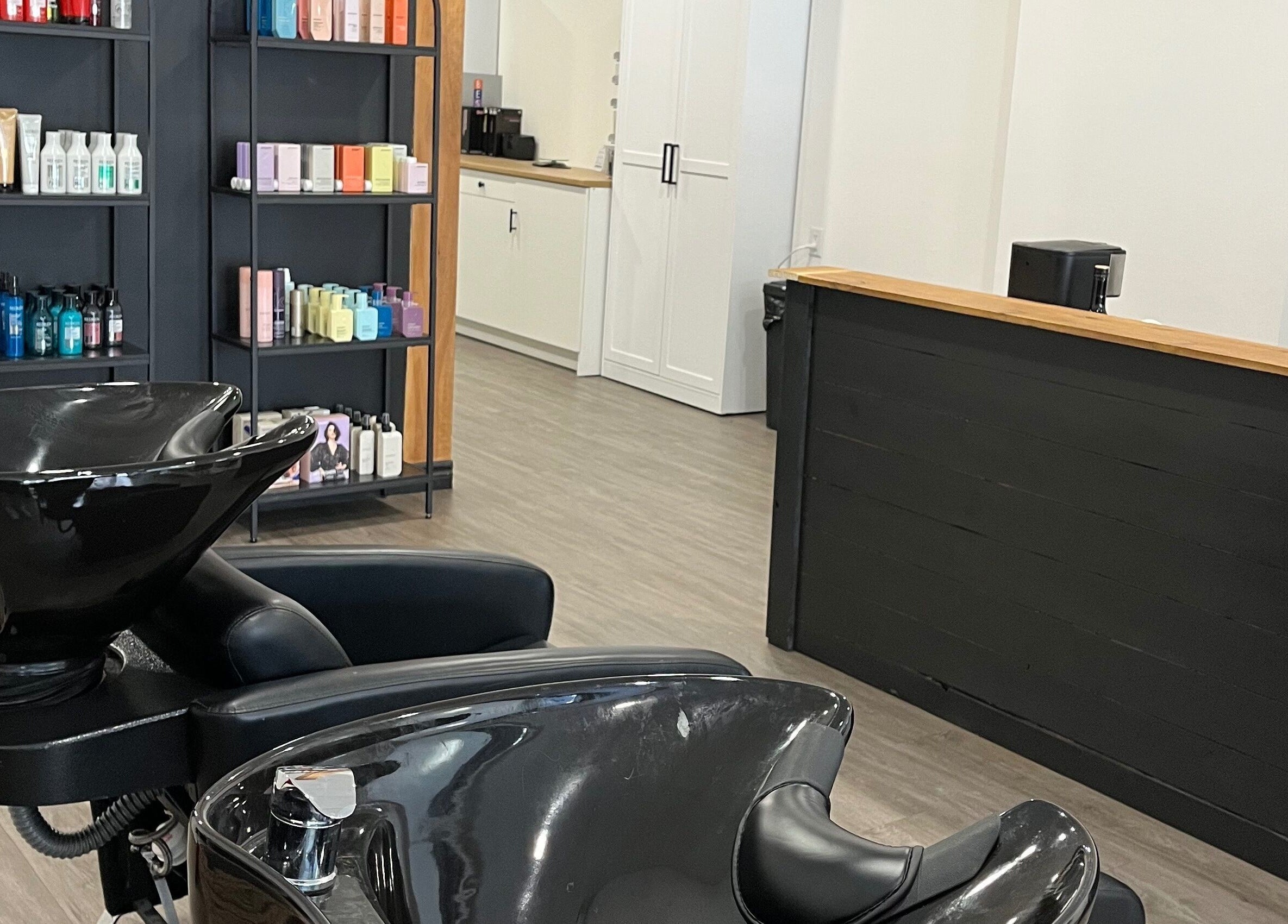 L'espace lavage moderne du salon Chez Madame C à Granby, Québec, CA, avec produits capillaires en arrière-plan.