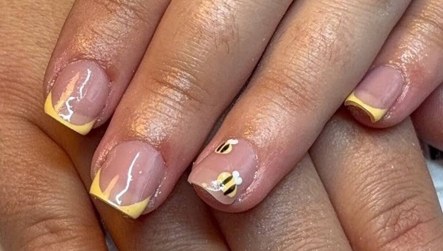 Stylish bee-themed nails with yellow French tips at Beauty By Poppy Marina, Bury, England, GB.