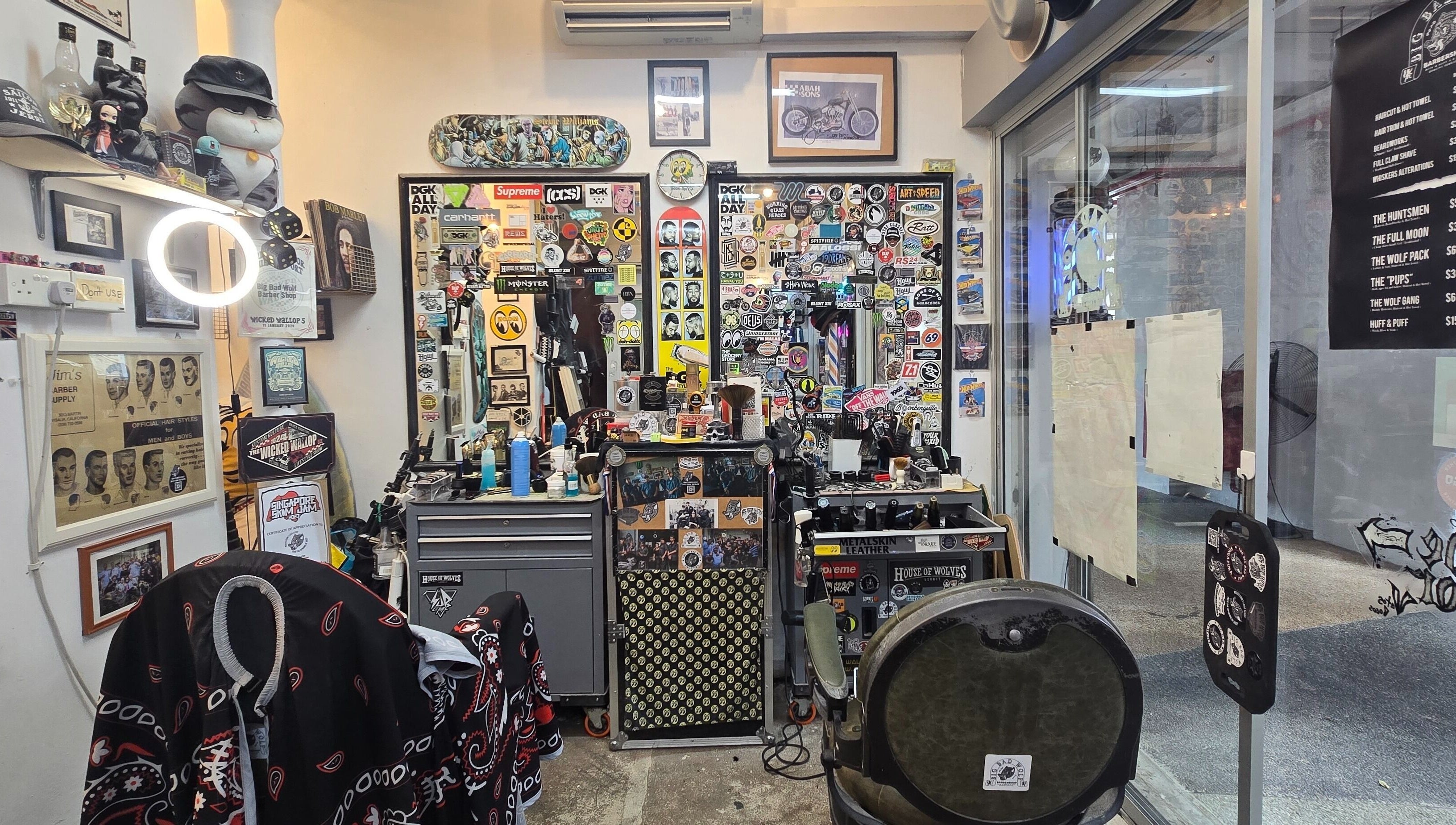 Interior of Big Bad Wolf Barbershop in Singapore, SG, showcasing vibrant sticker-covered walls and barber tools.