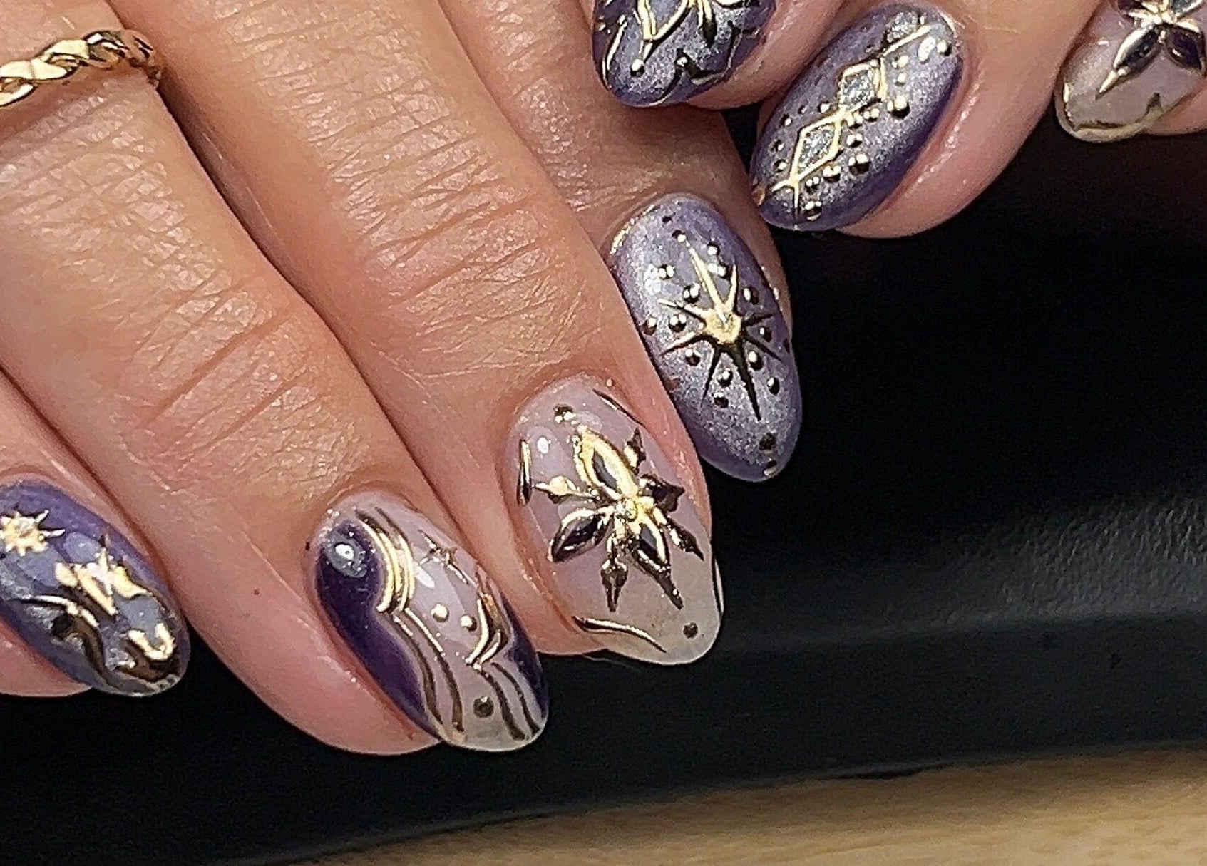 Elegant celestial-themed nails at Cured by Margaret, Guelph, Ontario, CA with intricate gold and purple designs.